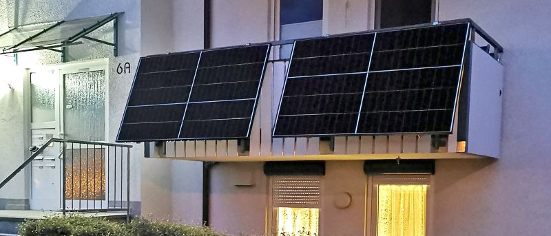 Hauseingang mit zwei Solarmodulen an der Balkonbrüstung darüber