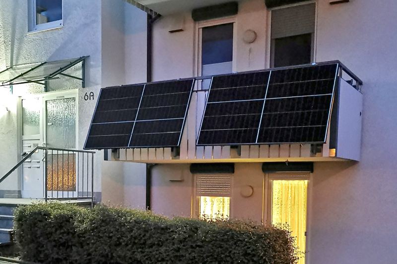 Hauseingang mit zwei Solarmodulen an der Balkonbrüstung darüber