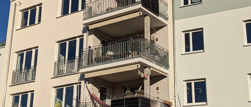Balkone eines Mehrfamilienhauses, an zwei Brüstungen hängen Solarmodule eines Balkonkraftwerks