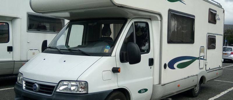 Weißes Wohnmobil auf einem Parkplatz