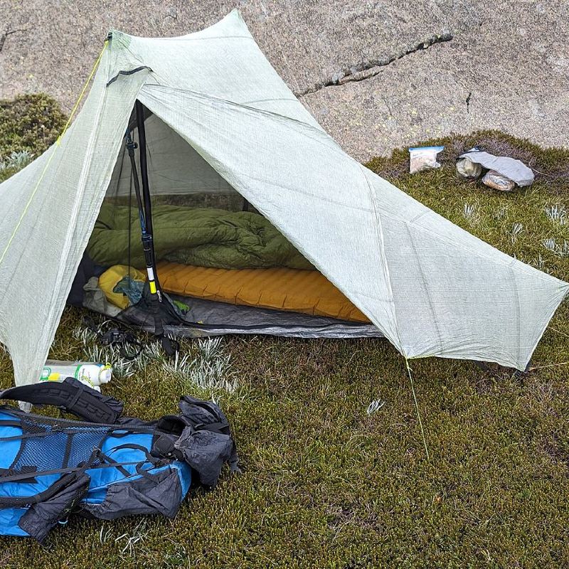 Leichtes Zelt mit Schlafsack und Rucksack auf einer Wiese